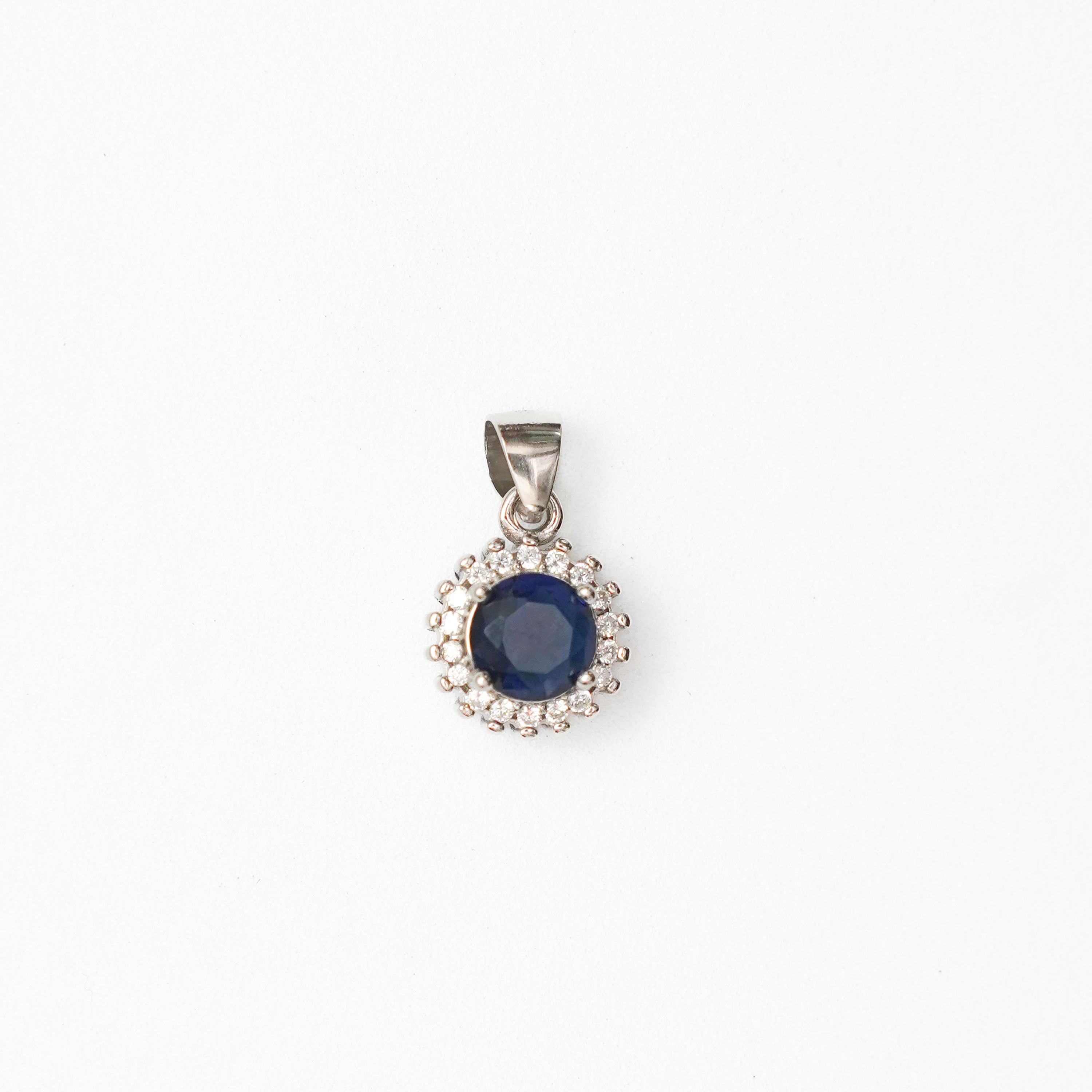 Silver pendant with a blue gemstone on a white background