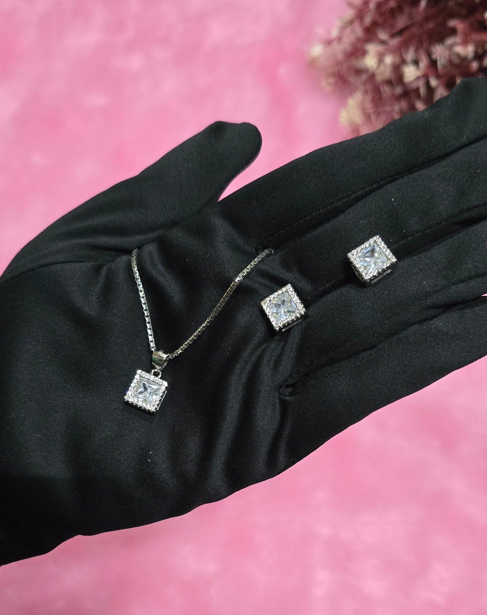Black glove with embedded silver jewelry on a pink background