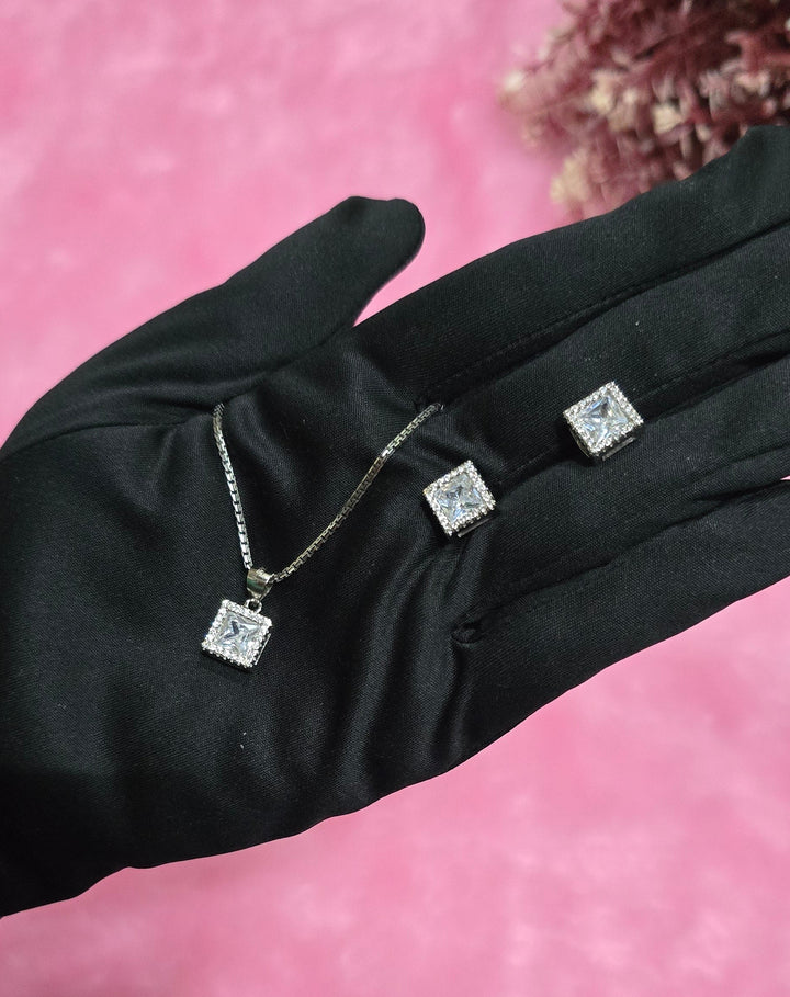 Black glove with embedded silver jewelry on a pink background